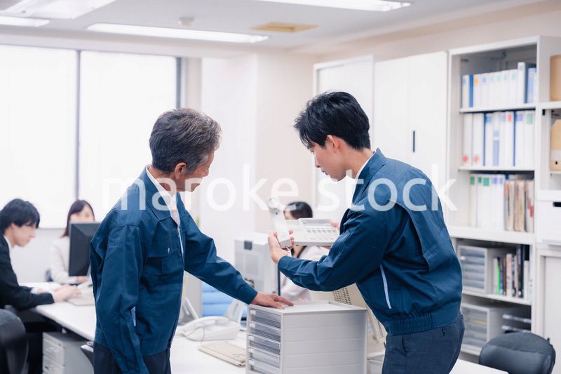 オフィスで電話機のメンテナンスをする作業員の男性