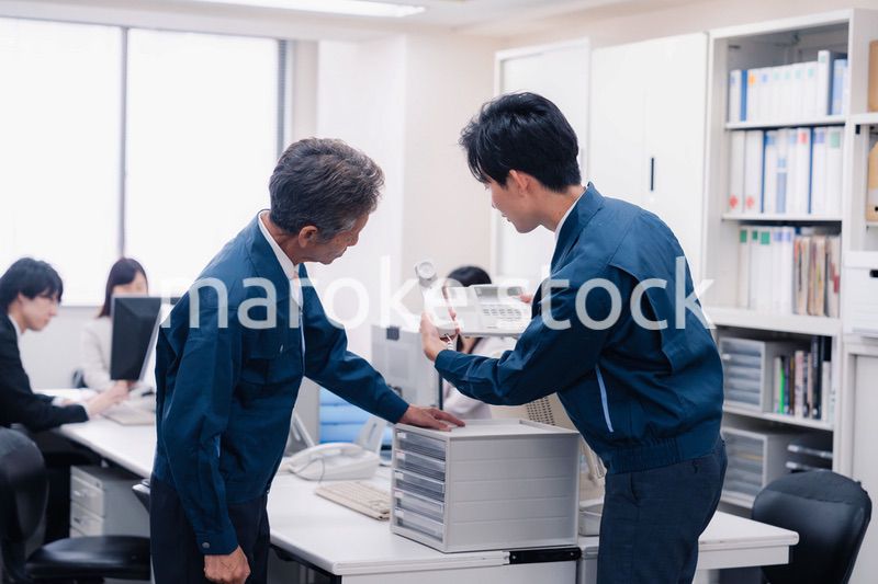 オフィスで電話機のメンテナンスをする作業員の男性