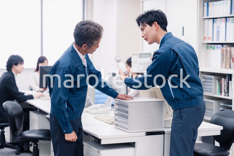 オフィスで電話機のメンテナンスをする作業員の男性