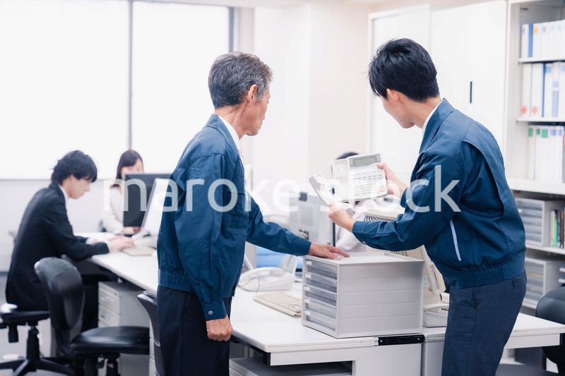 オフィスで電話機のメンテナンスをする作業員の男性