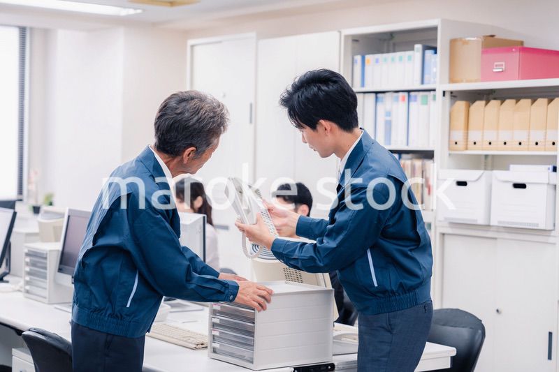 オフィスで電話機のメンテナンスをする作業員の男性