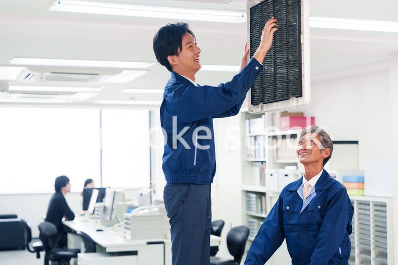 ビルのエアコンの点検をする作業服の男性