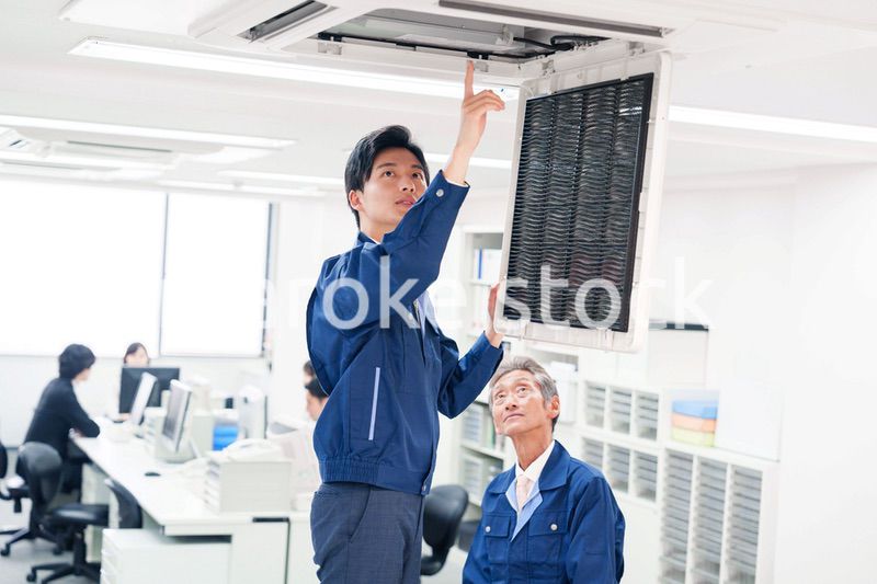 ビルのエアコンの点検をする作業服の男性