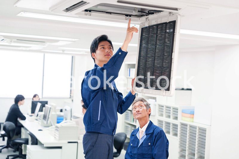 ビルのエアコンの点検をする作業服の男性