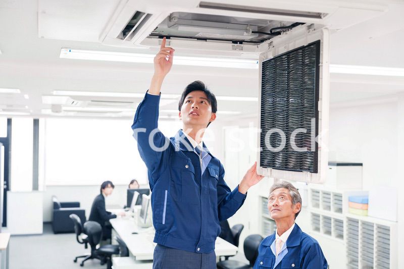 ビルのエアコンの点検をする作業服の男性
