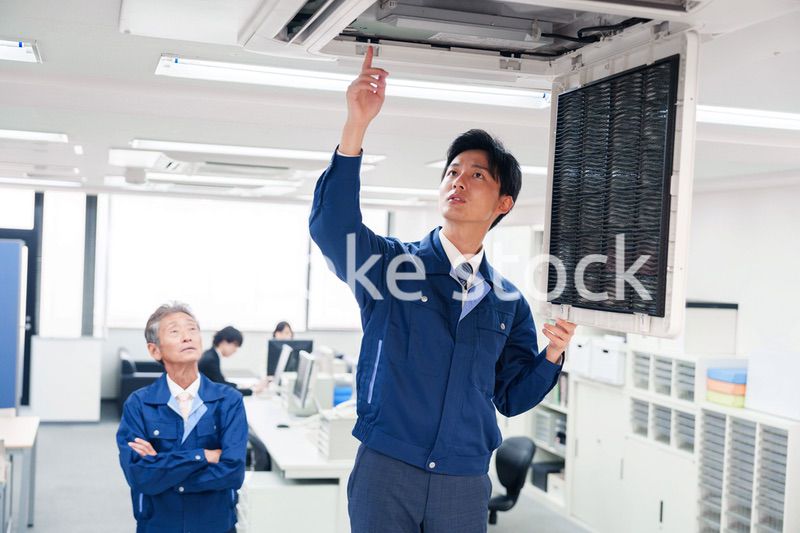 ビルのエアコンの点検をする作業服の男性