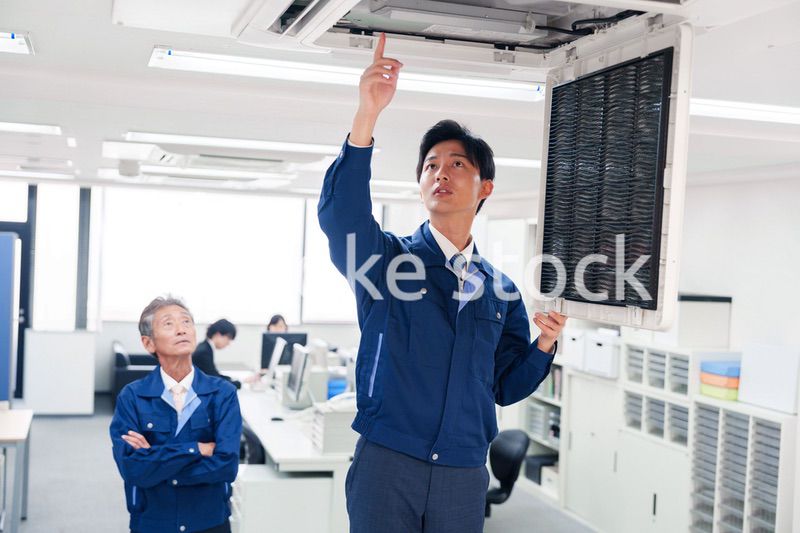ビルのエアコンの点検をする作業服の男性