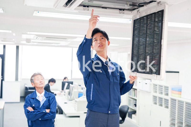 ビルのエアコンの点検をする作業服の男性