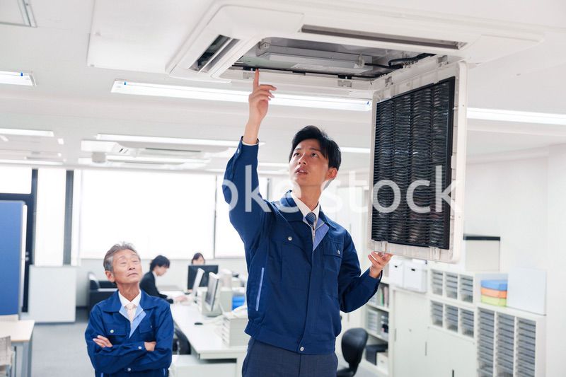 ビルのエアコンの点検をする作業服の男性