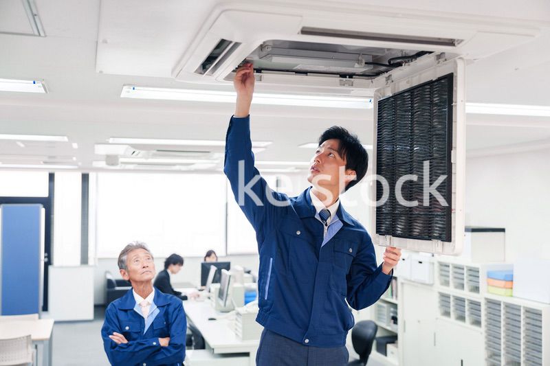 ビルのエアコンの点検をする作業服の男性