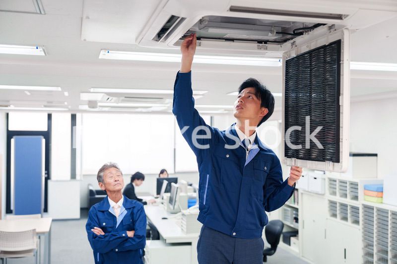 ビルのエアコンの点検をする作業服の男性