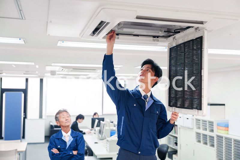 ビルのエアコンの点検をする作業服の男性