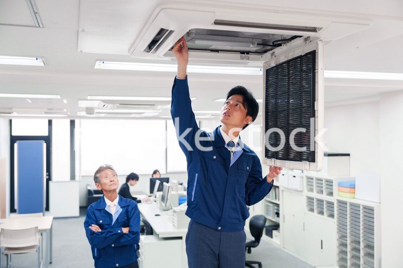 ビルのエアコンの点検をする作業服の男性