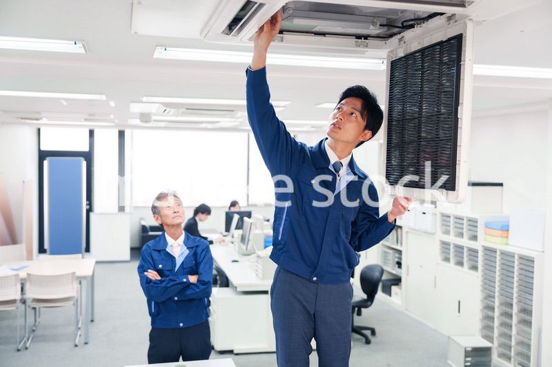 ビルのエアコンの点検をする作業服の男性