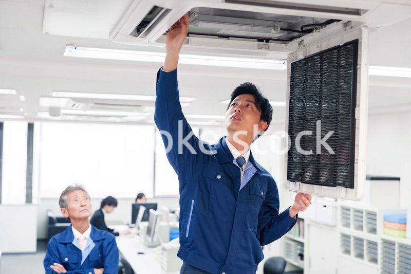 ビルのエアコンの点検をする作業服の男性