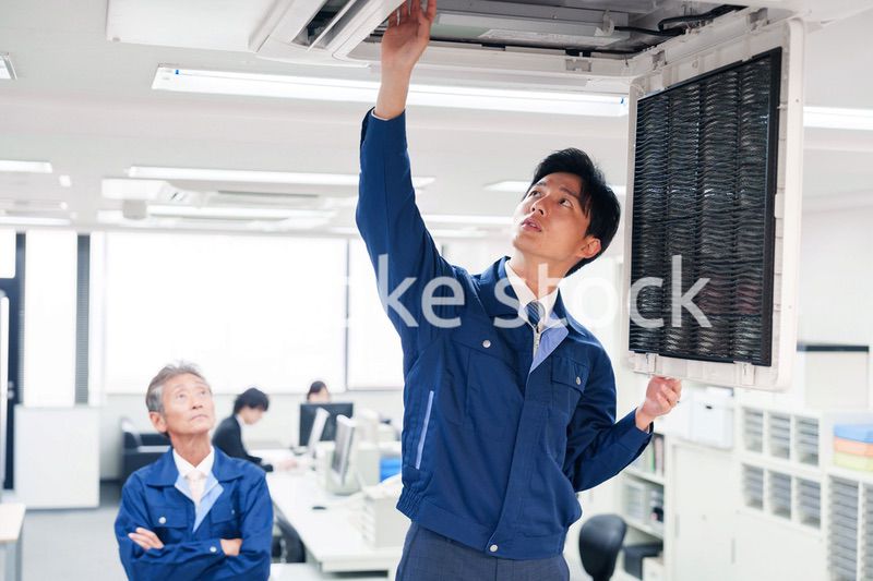 ビルのエアコンの点検をする作業服の男性