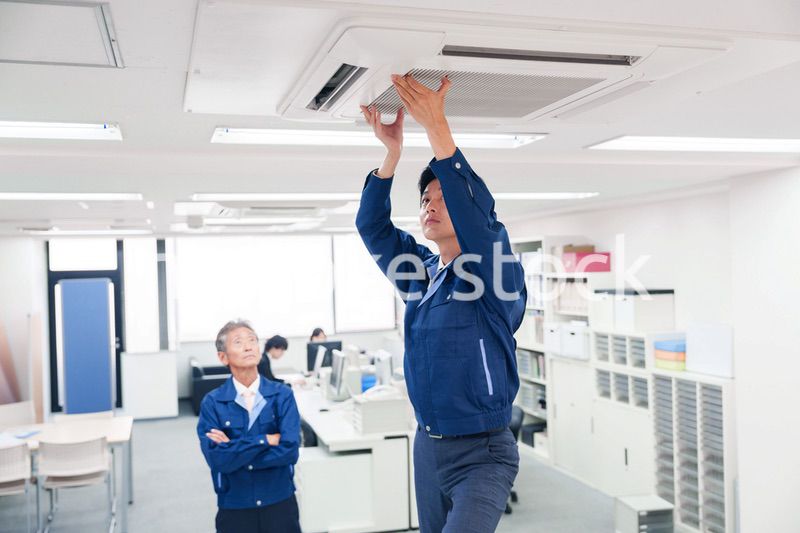 ビルのエアコンの点検をする作業服の男性