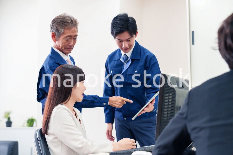 オフィスで話す作業服の人とスーツの女性