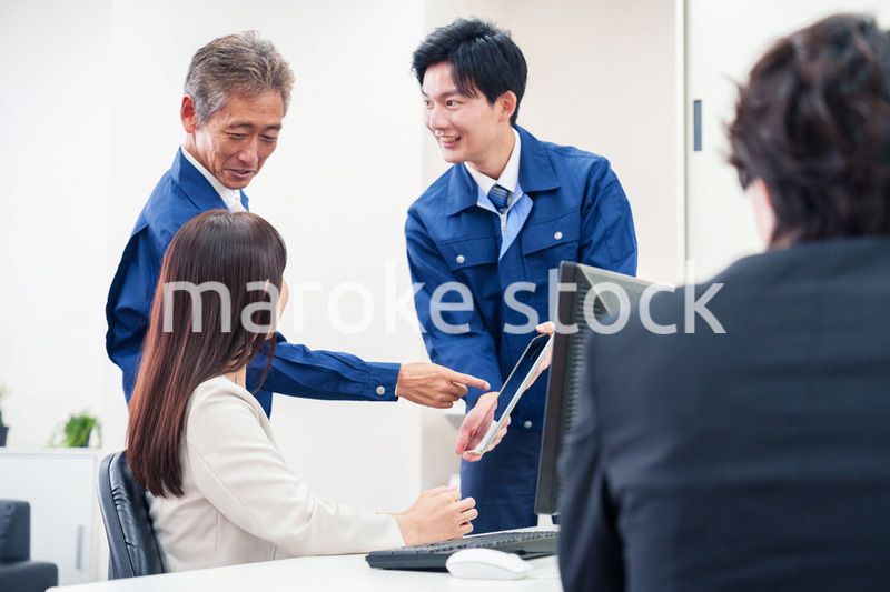 オフィスで話す作業服の人とスーツの女性