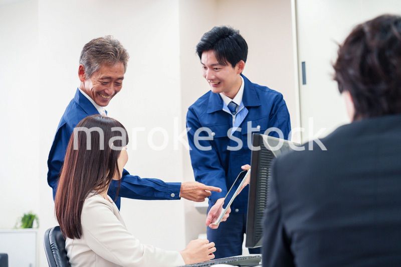 オフィスで話す作業服の人とスーツの女性