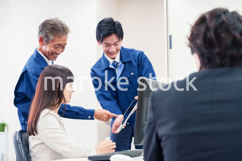 オフィスで話す作業服の人とスーツの女性