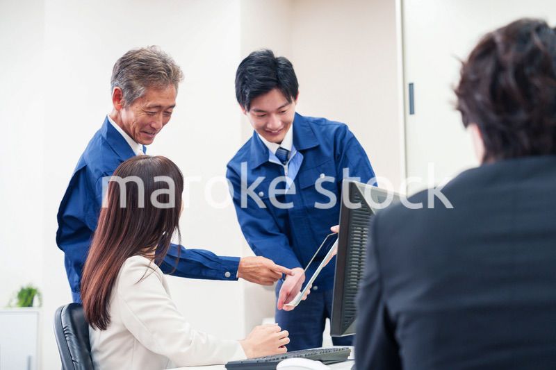 オフィスで話す作業服の人とスーツの女性