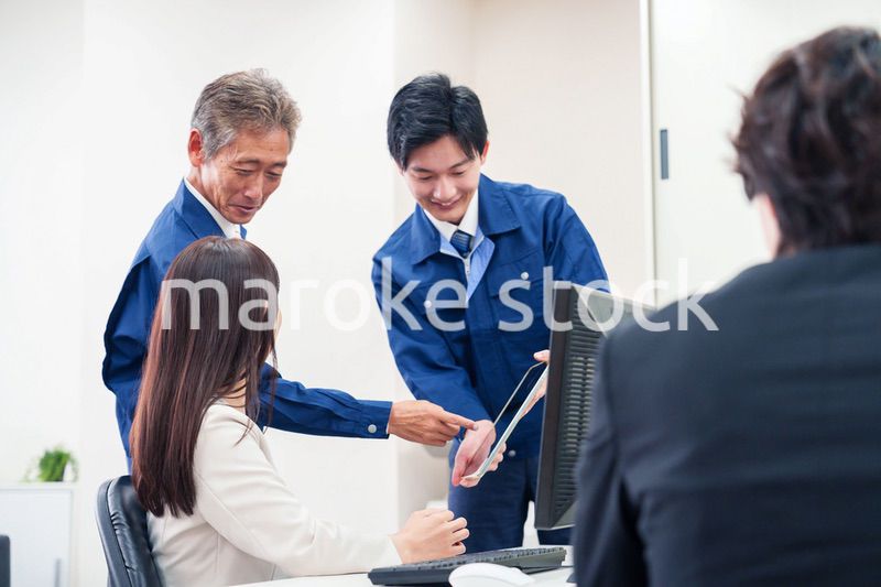 オフィスで話す作業服の人とスーツの女性