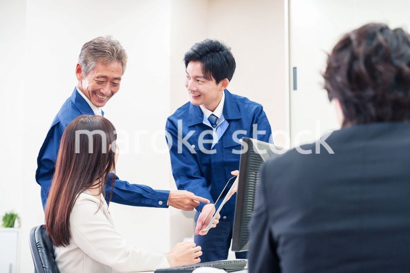 オフィスで話す作業服の人とスーツの女性