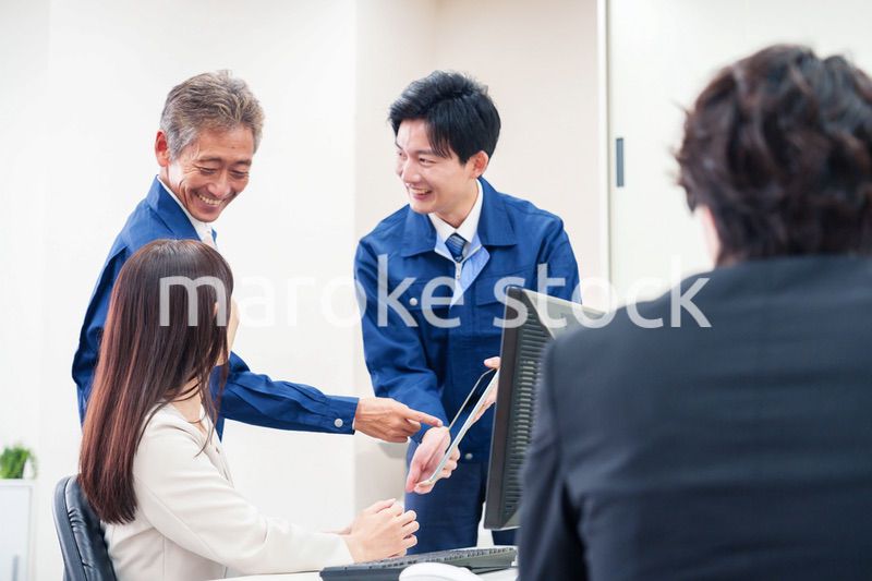 オフィスで話す作業服の人とスーツの女性