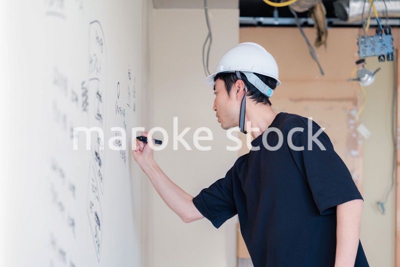 施工中の壁にメモを取る大工さん