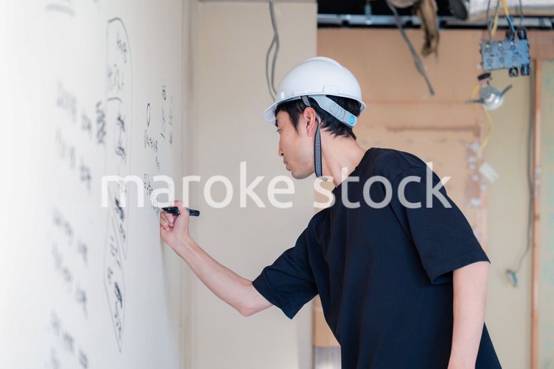 施工中の壁にメモを取る大工さん
