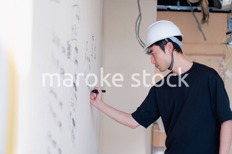 施工中の壁にメモを取る大工さん