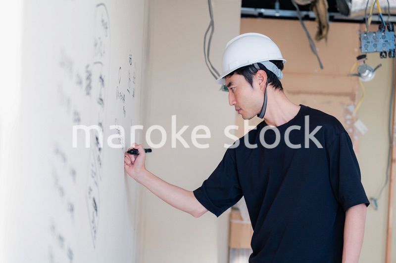 施工中の壁にメモを取る大工さん