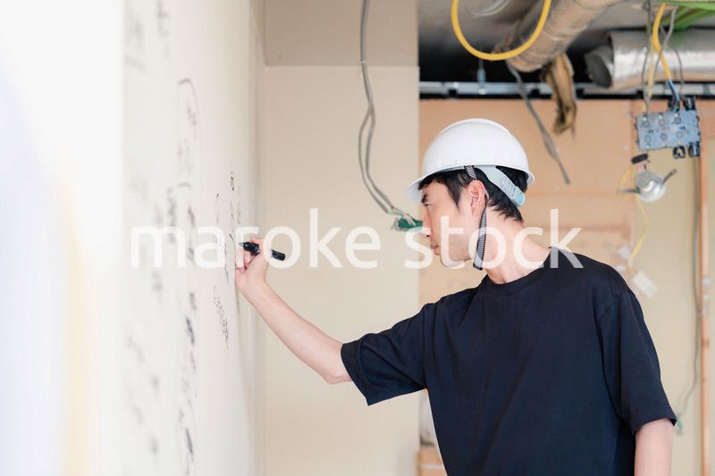 施工中の壁にメモを取る大工さん