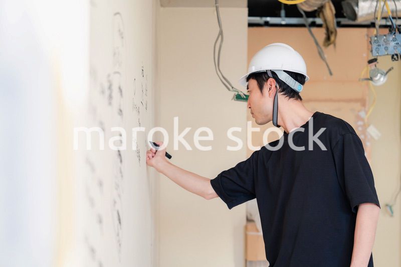 施工中の壁にメモを取る大工さん
