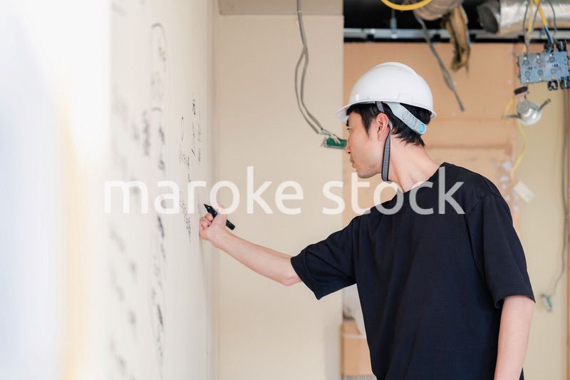 施工中の壁にメモを取る大工さん