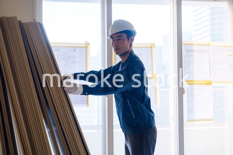 リフォーム工事の現場で石膏ボードを運ぶ職人