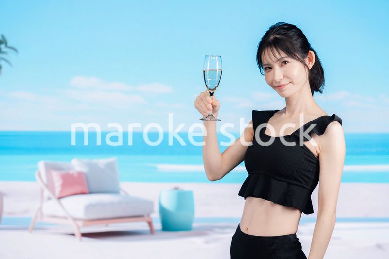 ビーチでスパークリングワインを飲む若い女性