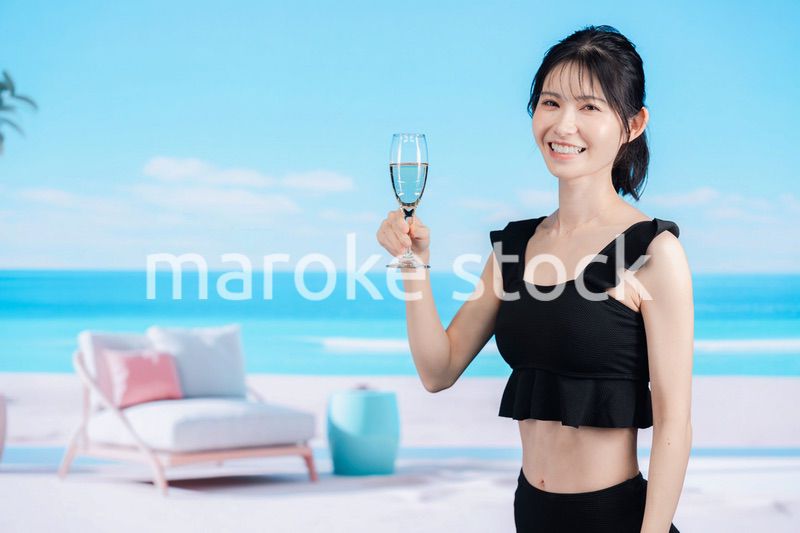 ビーチでスパークリングワインを飲む若い女性
