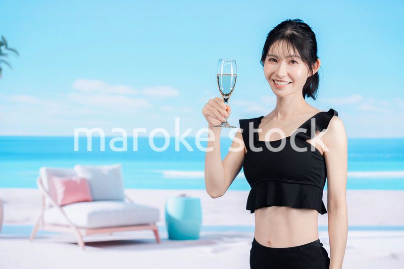 ビーチでスパークリングワインを飲む若い女性