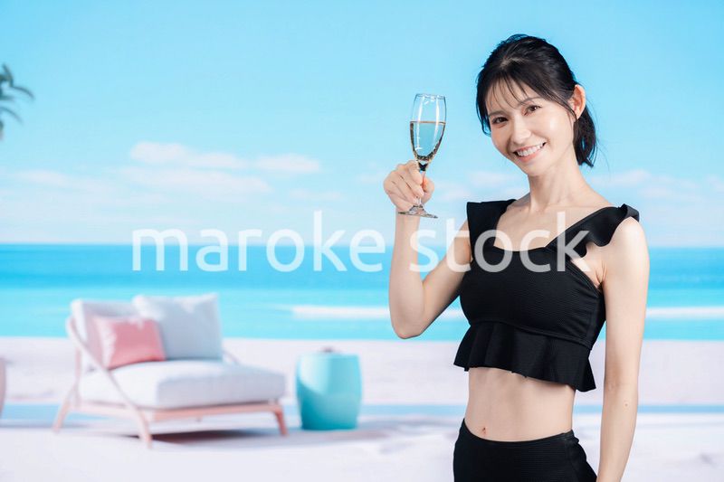 ビーチでスパークリングワインを飲む若い女性