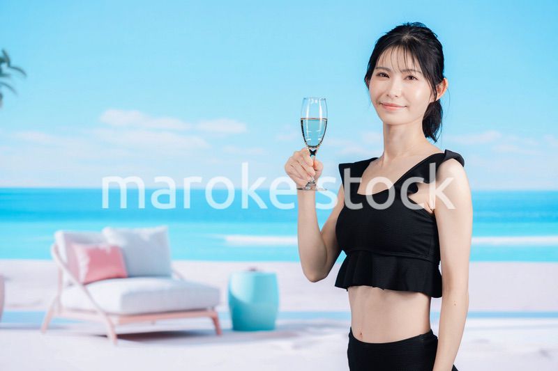 ビーチでスパークリングワインを飲む若い女性