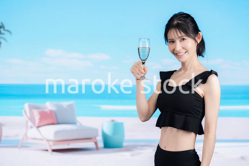 ビーチでスパークリングワインを飲む若い女性