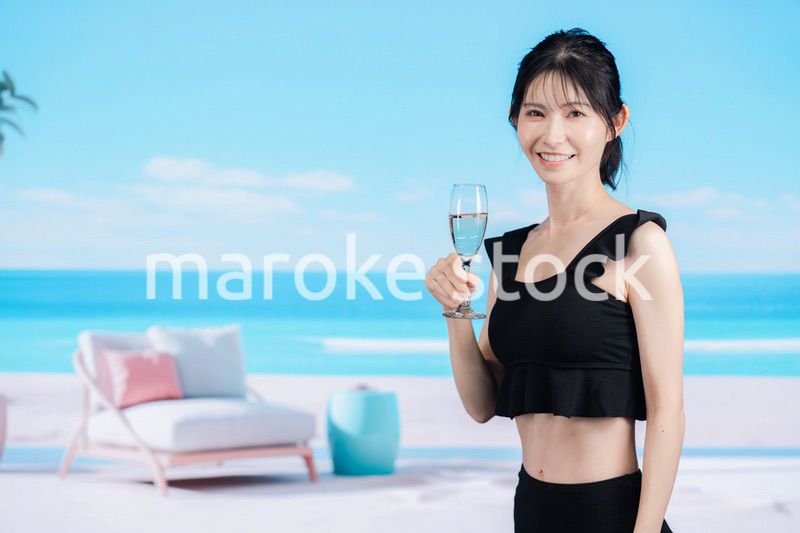 ビーチでスパークリングワインを飲む若い女性