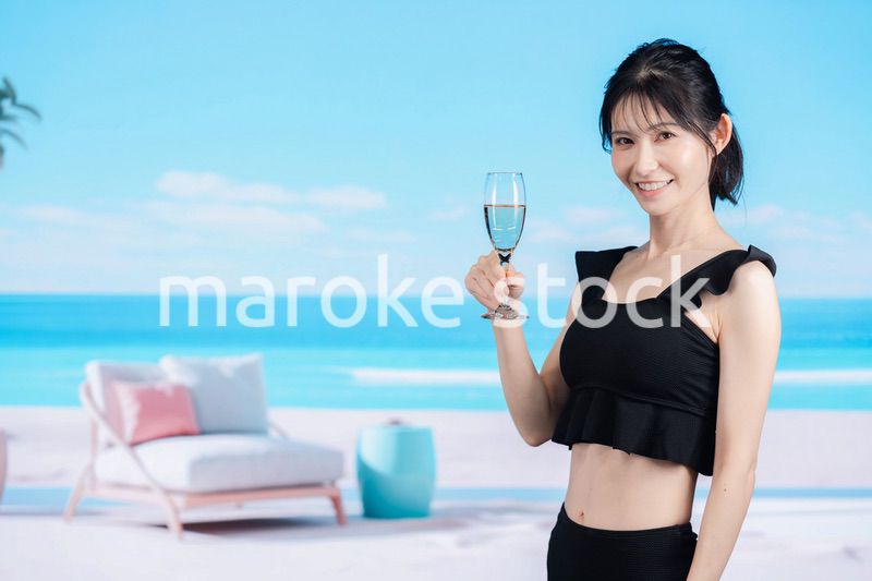 ビーチでスパークリングワインを飲む若い女性