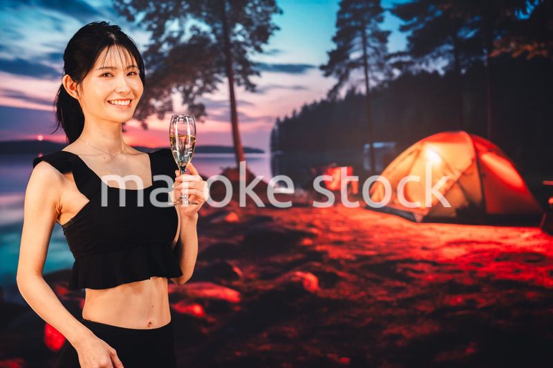キャンプをしながらスパークリングワインを飲む女性