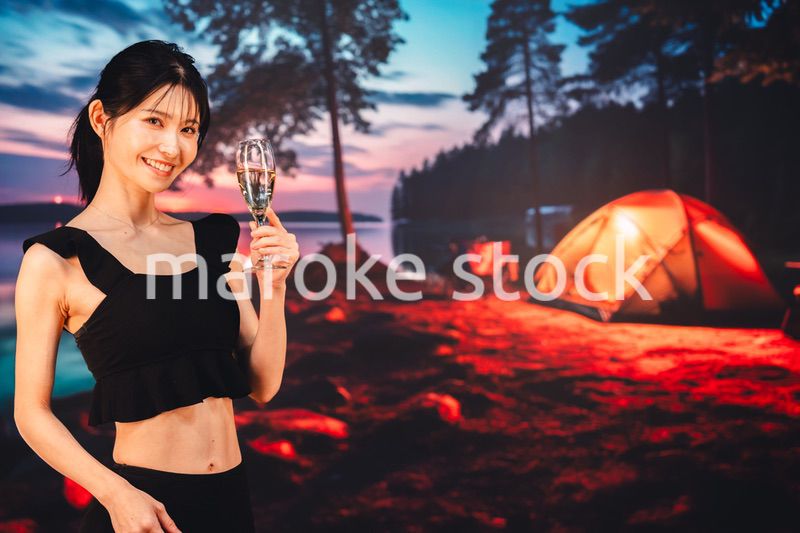 キャンプをしながらスパークリングワインを飲む女性