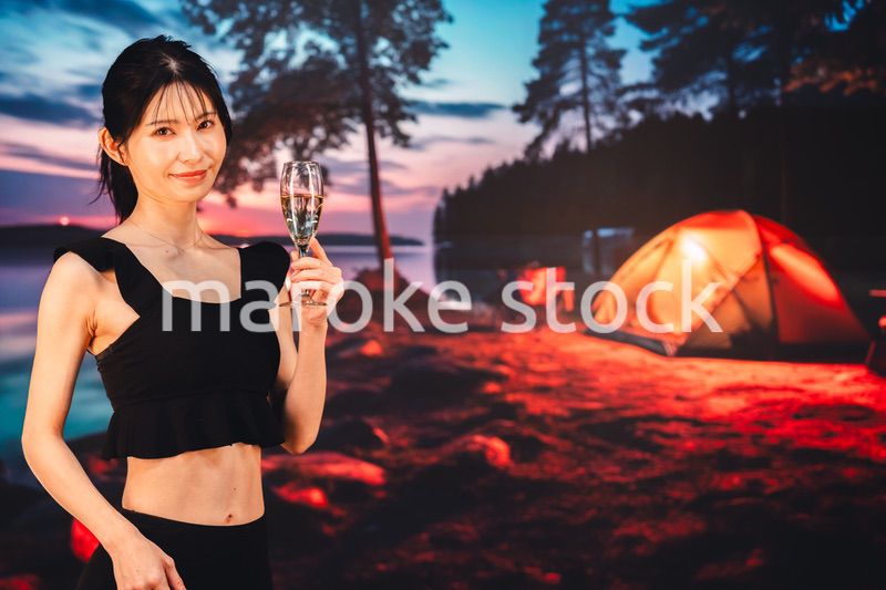 キャンプをしながらスパークリングワインを飲む女性