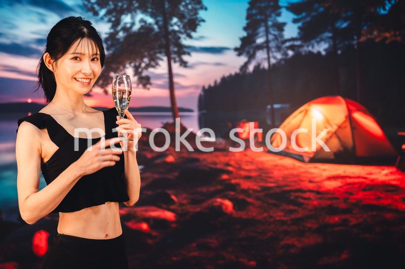 キャンプをしながらスパークリングワインを飲む女性
