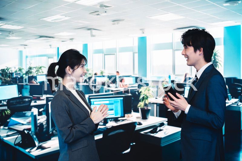 オフィスで楽しく話す男女のビジネスパーソン